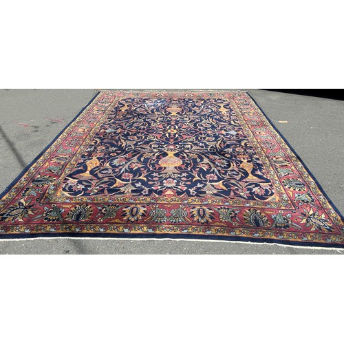 1701 - A large country house Persian design carpet, with vases of flowers and trailing flowers on a blue gr... 