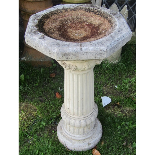 2062 - A weathered two sectional cast composition stone bird bath with octagonal top, raised on a fluted pe... 