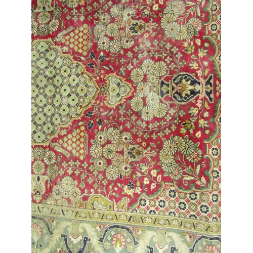 2744 - A Persian hand-knotted wool rug with vases of flowers and a scrolling floral border, in tones of cri... 