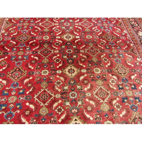 2750 - A large country house Persian design Rug, hand-knotted with repeated floral pattern on a red ground,... 