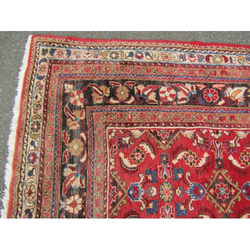 2750 - A large country house Persian design Rug, hand-knotted with repeated floral pattern on a red ground,... 