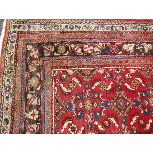 2750 - A large country house Persian design Rug, hand-knotted with repeated floral pattern on a red ground,... 