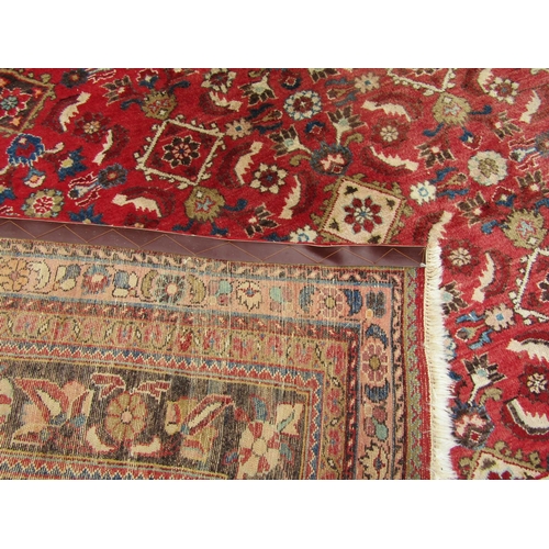 2750 - A large country house Persian design Rug, hand-knotted with repeated floral pattern on a red ground,... 