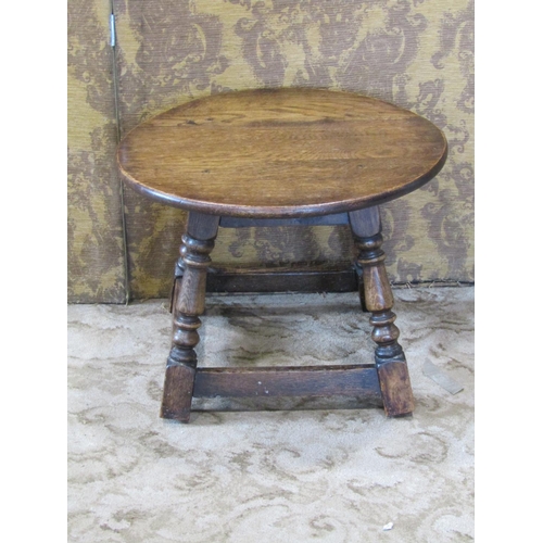 A small old English oak occasional table, the circular top raised on four splay supports, 50 cm diameter