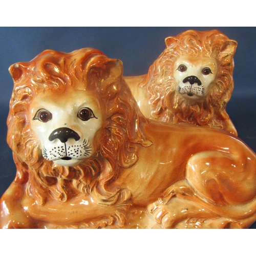 1037 - A pair of late 19th century Staffordshire models of recumbent lions with glass eyes