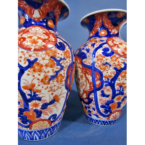 1082 - A pair of 19th century Imari vases in a red and blue colourway with repeating geometric detail, 32cm... 