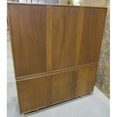 2205 - An Ercol golden dawn elm cabinet, the lower section enclosed by three panelled doors, the upper sect... 