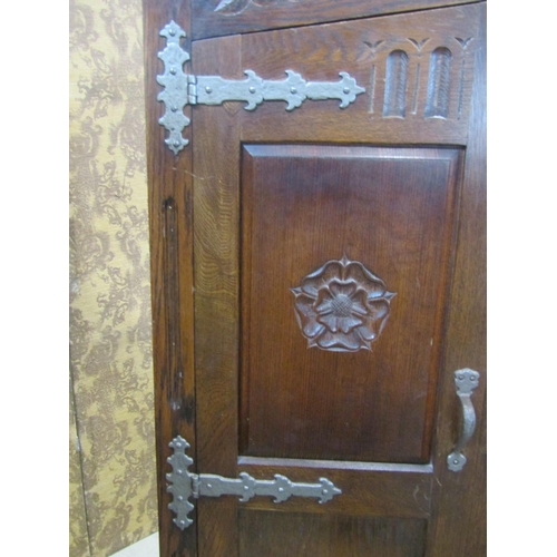 2243 - An old English style oak wardrobe with Tudor Rose detail, applied iron work set within a panelled fr... 