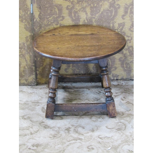 2303 - A small old English oak occasional table, the circular top raised on four splay supports, 50 cm diam... 