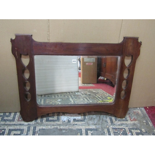 2419 - A mahogany framed wall mirror in the Arts & Crafts style with pierced border enclosing a bevelled pl... 