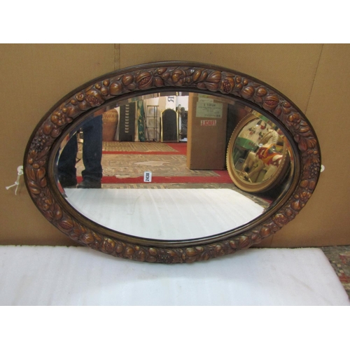 2422 - A 20th century carved wall mirror of oval form, loosely in the Black Forest style, enclosing a bevel... 