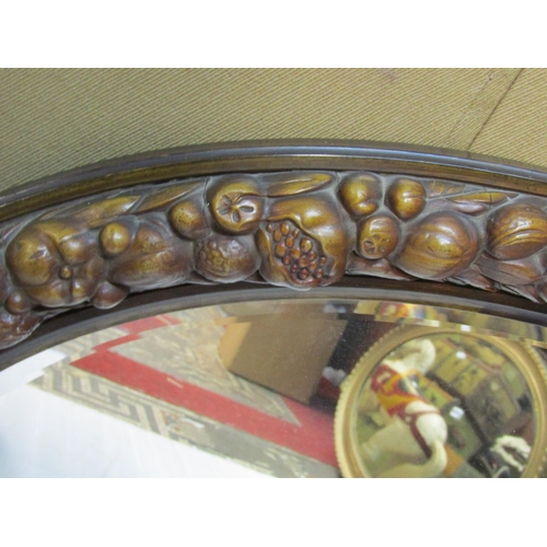 2422 - A 20th century carved wall mirror of oval form, loosely in the Black Forest style, enclosing a bevel... 