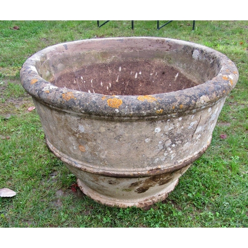 A large weathered composition stone garden planter of circular tapered ribbed form, 87cm diameter x 60cm high (af repair to rim)