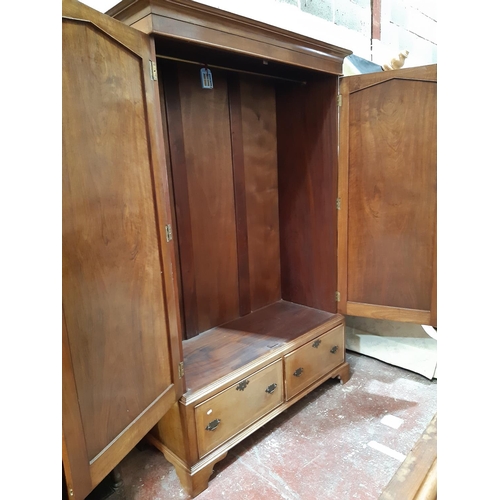 2444 - A walnut wardrobe enclosed by two panelled doors over two frieze drawers with brass fittings, 140cm ... 