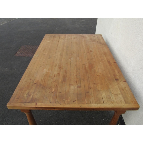 2464 - A contemporary stripped pine farmhouse kitchen table, the planked top raised on turned legs with two... 