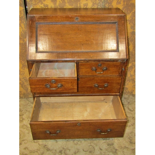 2354 - An Edwardian oak bureau of two long and two short drawers, the fall flap enclosing a fitted interior... 