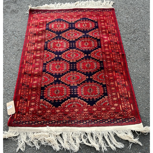 2705 - A Bokhara rug with a field of ten red guls on a blue ground with geometric borders, 150cm x 100cm