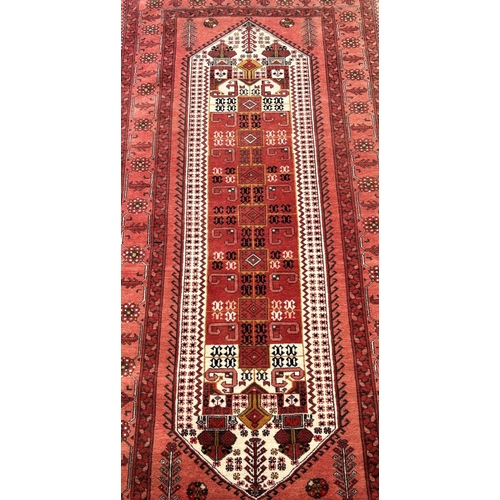 2706 - A corridor carpet of middle eastern design, with central elongated lozenge panel on a faded pink gro... 