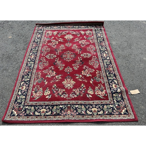 2714 - A modern machine made carpet with all over floral pattern on a red ground, 230cm x 160cm