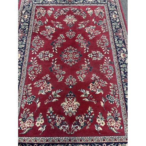 2714 - A modern machine made carpet with all over floral pattern on a red ground, 230cm x 160cm