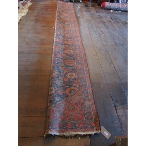 2729 - An old eastern wool runner, the central dark blue ground supporting abstract floral detail, within f... 