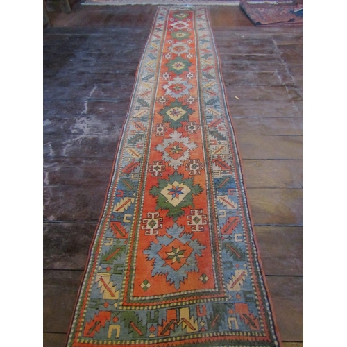 2718 - A long wool runner with ten medallion centre, upon a brick red field within geometric running border... 