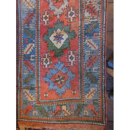 2718 - A long wool runner with ten medallion centre, upon a brick red field within geometric running border... 