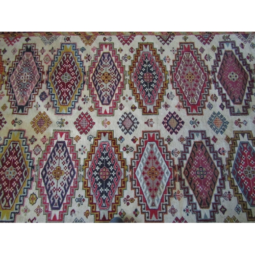 2727 - An eastern wool rug with beige field, with sixteen lozenge shaped medallions, further geometric deta... 