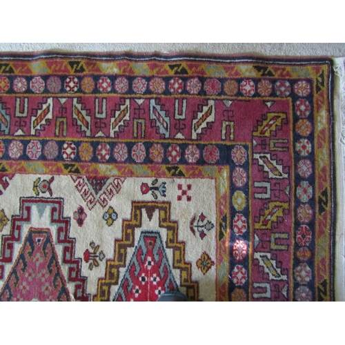 2727 - An eastern wool rug with beige field, with sixteen lozenge shaped medallions, further geometric deta... 