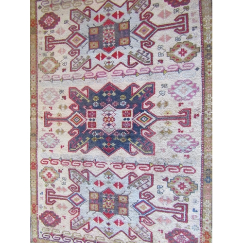 2716 - A wool rug in the eastern manner with triple medallion upon a pale cream field, within running borde... 