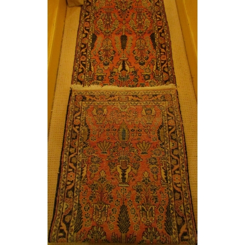 2725 - A very long eastern style runner, with repeating floral and vase detail, upon a pink ground within n... 