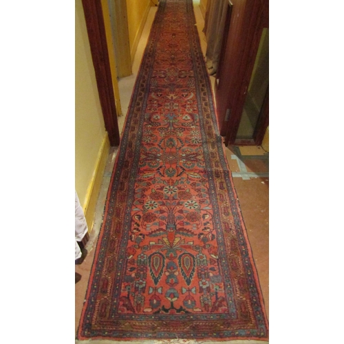 2725 - A very long eastern style runner, with repeating floral and vase detail, upon a pink ground within n... 