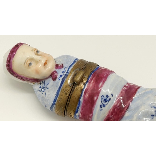 1090 - An unusual porcelain bodkin case, in the form of a foundling wrapped in swaddling, the hinged cover ... 