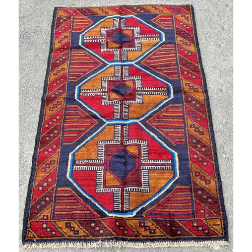 2708 - A new Baluchi carpet, with large elephant foot gul in tones of red and orange, 142cm x 89cm