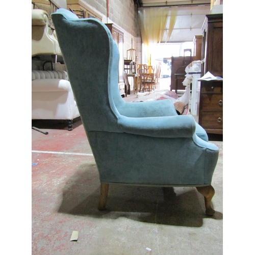 2452 - A Georgian style wing chair with scrolled arms on short cabriole supports