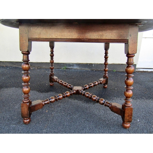 2467 - An old English style oak dining table the circular top raised on bobbin supports united by a matchin... 