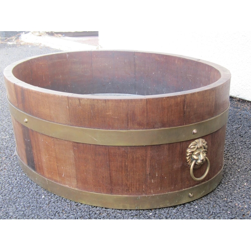 2496 - A Lister & Co teakwood jardinière/wine cooler of oval form, brass banded with lion mask ring named G... 