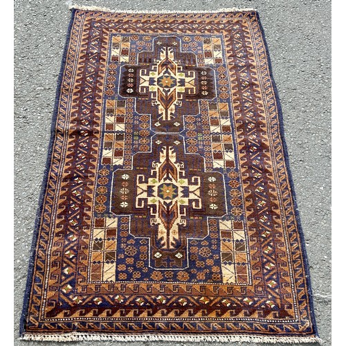 2740 - An old Baluchi rug with a pair of elongated central medallions in tones of brown and blue, 137 x 84c... 