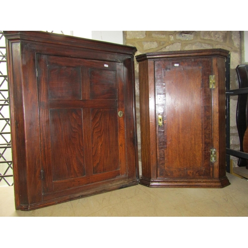 2164 - A Georgian elm country made hanging corner cupboard enclosed by a panelled door,  a further example ... 