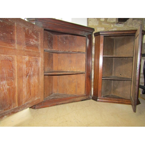 2164 - A Georgian elm country made hanging corner cupboard enclosed by a panelled door,  a further example ... 