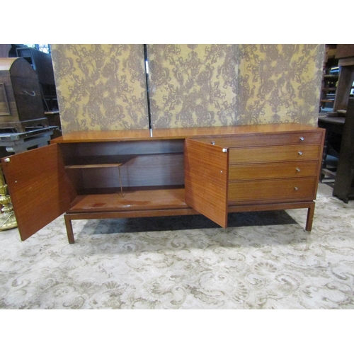 2257 - A mid century teak sideboard enclosed by two panelled doors and four graduated drawers on square cut... 