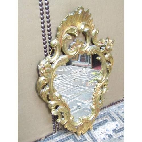 2412 - A rococo style gilded wall mirror with C scroll, floral and other detail, 80cm x 50cm