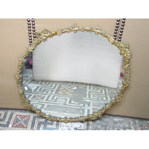 2416 - An oval wall mirror in a cast brass frame with fruit and floral detail, 89cm max