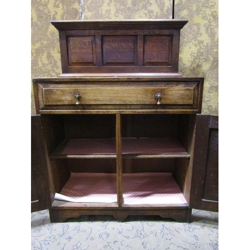 2247 - A craftsman made oak side cupboard in the Cotswold school manner enclosed by a pair of fielded panel... 