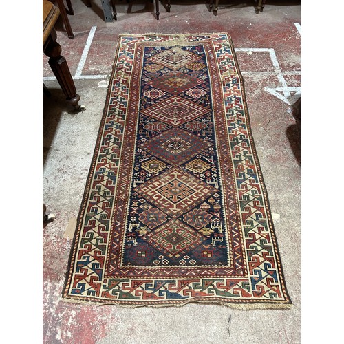 2722 - A Kazak runner with six hooked medallions on a blue ground, 240 cm x 105cm approx. (Worn & torn).