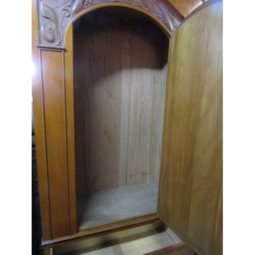 2358 - A good quality art nouveau wardrobe in satin walnut, the arched mirror panelled door beneath a carve... 