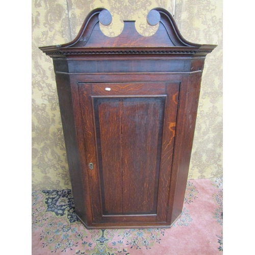 2636 - A Georgian oak hanging corner cupboard set beneath a swan neck pediment, 130cm high