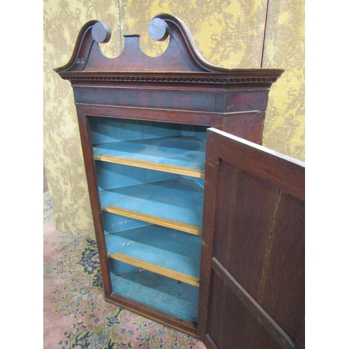 2636 - A Georgian oak hanging corner cupboard set beneath a swan neck pediment, 130cm high