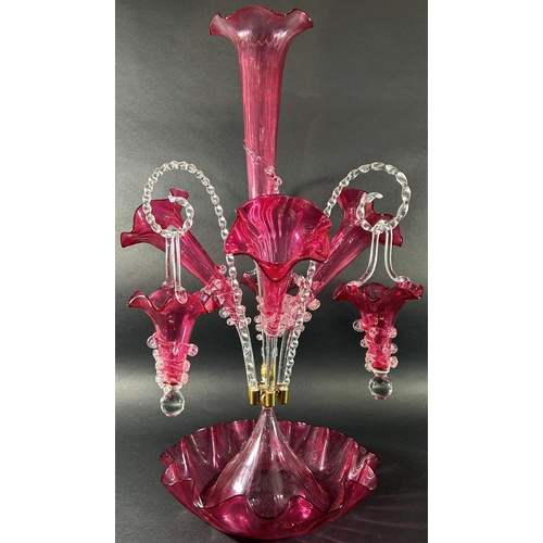 1119 - A 19th century cranberry glass epergne with four trumpets and three clear crook-shaped rope twist ar... 