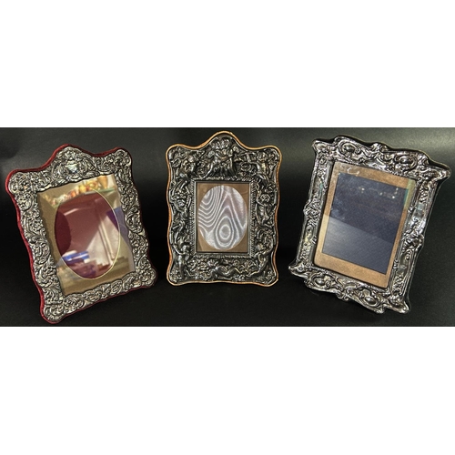 1179 - A silver photo frame with a floral embossed frame, 14 cm x 9.5 cm opening, together with two silver ... 